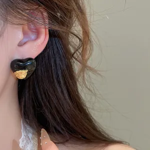 Nahaufnahme eines Vintage-Herzohrsteckers mit goldenem Blatt am Ohr des weiblichen Modells