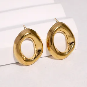 Close-up view of chunky gold-plated irregular geometric hoop stud earrings on white stand