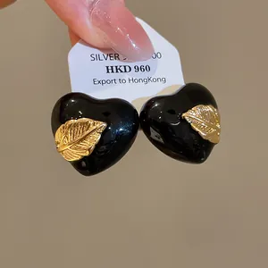 Nahaufnahme von luxuriösen schwarzen Emaille-Herzohrringen mit 18 Karat Blattgold-Dekor