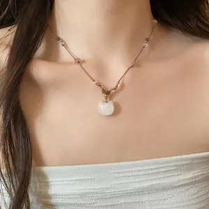 Détail d'un collier fait main avec pendentif chat et perles sur cordon en cuir brun.