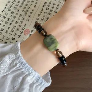 Gedetailleerd overzicht van houten kralenarmband in nieuwe Chinese stijl met groene steen op pols