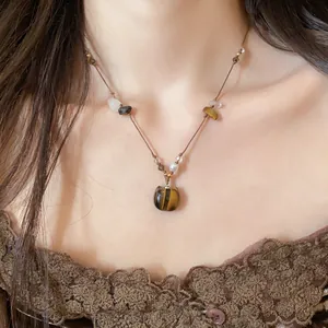 Détail d'un collier vintage avec pendentif chat en œil de tigre et cordon perlé