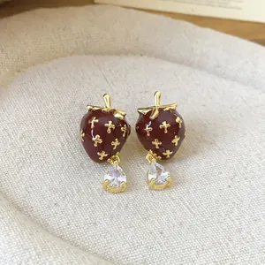 Close-up of vintage enamel strawberry stud earrings with pear-shaped zircon drops.