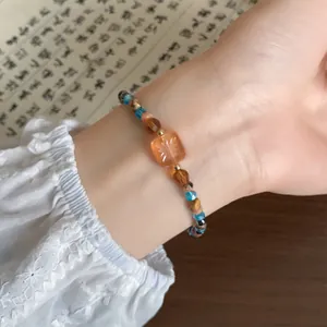 Close-up van een kralenarmband in Chinees-stijl met een gegraveerde oranje kraal