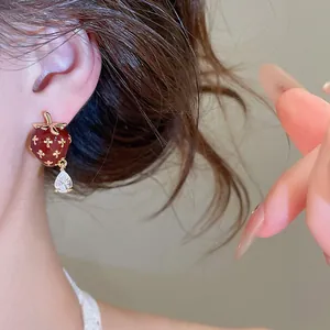 Macro view of vintage red enamel strawberry earrings with a teardrop zircon pendant