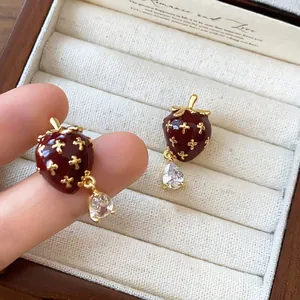Detailed view of vintage red enamel strawberry earrings with teardrop zircon.