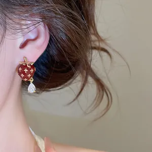 Detailed view of red enamel strawberry stud earring with a teardrop zircon on a model