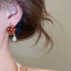 Close-up view of vintage red enamel strawberry stud earring with sparkling zircon drop