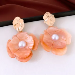 Close-up of acrylic flower earrings with marbled petals and pearl center