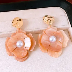 Detailed close-up of peach acrylic flower earrings with center pearl and gold pleated studs