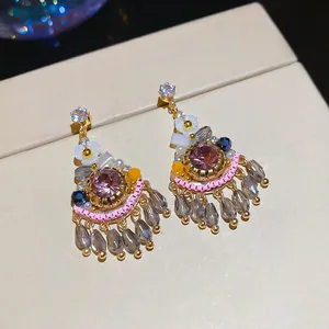 Close-up of elegant Bohemian earrings featuring pink crystals and teardrop beaded fringes.