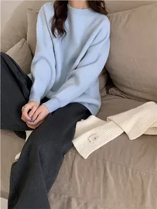 Détail lifestyle d'un pull en maille bleu clair à coupe ample pour femme dans un cadre chaleureux.