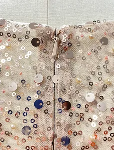 Close-up detail showing exquisite rose gold sequins and pearls on an elegant evening gown