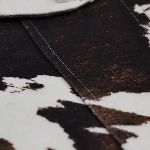 Detailopname van de zachte textuur en de witte stiksels van een jas met koeprint