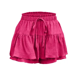 Dettaglio della gonna pantalone rosa acceso con volant, coulisse e tessuto texturizzato.