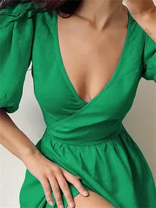 Detail of green puff sleeve wrap dress showing V-neckline and waist tie design.