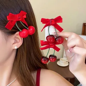 Elegante Haarklammern mit roter Samtschleife und Kirschanhängern, getragen von einem Modell.