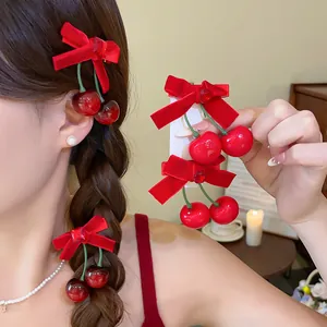 Detailansicht roter Haarklammern mit beflockter Schleife und Kirsch-Anhängern im Haar.