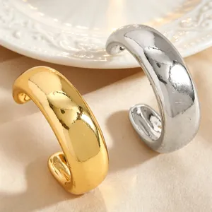 Gros plan de boucles d'oreilles ear cuff épaisses en or et argent sur fond élégant.