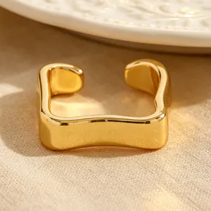Gros plan d'un ear cuff doré minimaliste et ondulé sur un fond en tissu neutre