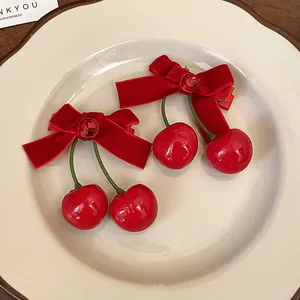 Detailaufnahme von zwei kirschroten Samtschleifen-Haarspangen auf einem Keramikteller.