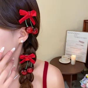 Detailansicht eleganter roter Haarklammern mit Flocked-Schleife und Kirschanhängern im Haar