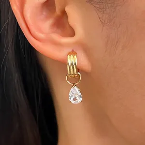 Gros plan d'une boucle d'oreille dorée avec un oxyde de zirconium en forme de poire