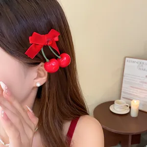 Nahaufnahme einer Haarspange mit roter Schleife und Kirsch-Anhänger an einem Model