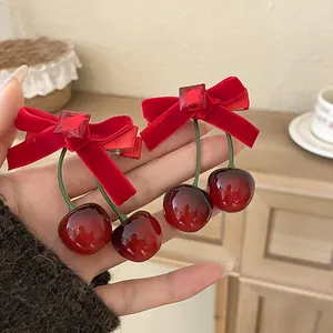 Nahaufnahme von eleganten beflockten Haarklammern mit Kirsch-Anhängern und roten Strasssteinen.