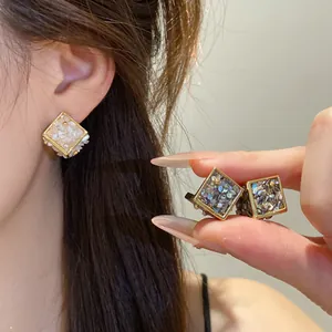 Gros plan de boucles d'oreilles losanges géométriques élégantes avec détails nacre