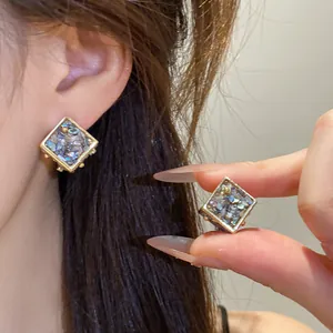 Gros plan de boucles d'oreilles losanges avec incrustation de coquillages