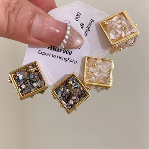 Gros plan de boucles d'oreilles carrées avec incrustation de coquillages et finition dorée