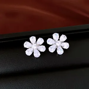 Primer plano de pendientes de flor con circonitas brillantes y pétalos de pera.