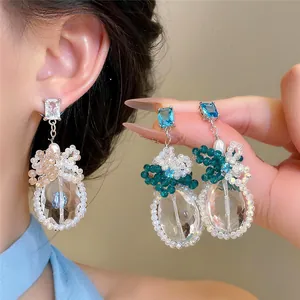 Dettaglio ravvicinato di eleganti orecchini con zirconi e perle e accenti colorati.