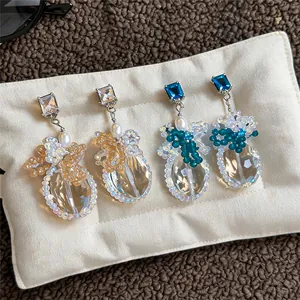 Vista dettagliata di eleganti orecchini con cristalli e perle su un supporto bianco.
