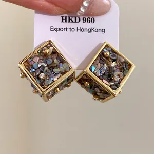 Gros plan de boucles d'oreilles cube géométriques avec des incrustations de nacre irisées