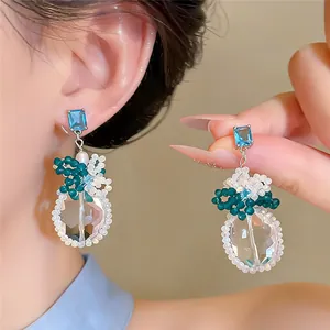 Dettaglio di orecchini pendenti in cristallo con zircone blu e fiori di perline