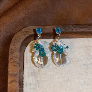 Dettaglio di lussuosi orecchini a goccia con zircone blu e pendenti in cristallo sfaccettato