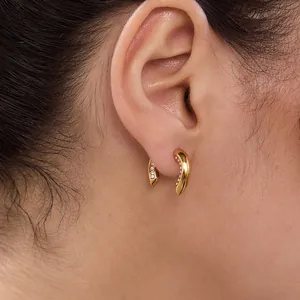 Primo piano di eleganti orecchini a forma di U dorati con strass indossati sull'orecchio