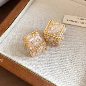 Vue rapprochée détaillée des boucles d'oreilles cubes dorées avec incrustations de nacre