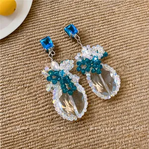 Dettaglio di orecchini pendenti vintage con zircone blu e gocce sfaccettate trasparenti