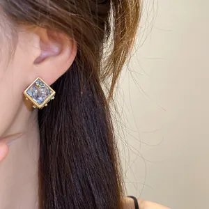 Gros plan de boucles d'oreilles losange géométriques dorées avec incrustation