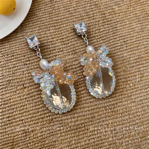 Dettaglio di orecchini ad ago in argento con zirconi, perle e ciondoli di cristallo.