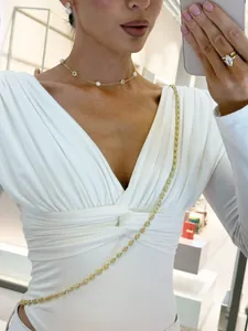 Detalle del top de modal blanco con cuello en V, elegante drapeado en la cintura y manga larga