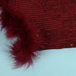 Macro view of burgundy sequins and soft ostrich feather trim on a sexy evening dress
