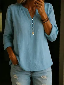 Detail of a stylish blue cotton linen long-sleeved V-neck tunic with white buttons