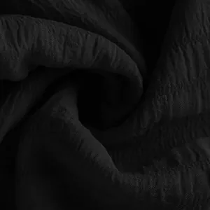 Close-up detail showing the high-quality black crinkled texture of summer sports shorts.