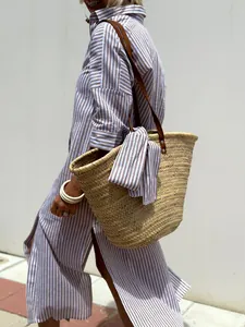 Side view of woman in striped midi shirt dress with side slits and straw bag