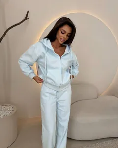 Full body view of a woman wearing a light blue zip-up hoodie and sweatpants set.