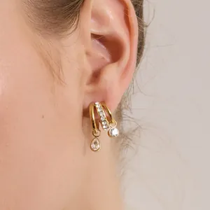 Détail rapproché de boucles d'oreilles en acier doré en forme de C serties de strass brillants